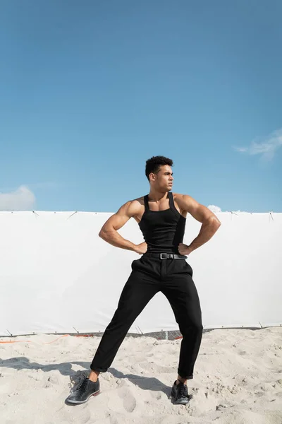 Strong cuban man in stylish black outfit holding hands on hips in Miami, south beach — Stock Photo