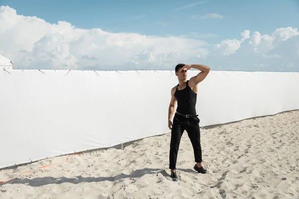 Homem cubano jovem e forte em roupa preta cobrindo rosto com a mão em Miami, praia sul — Fotografia de Stock