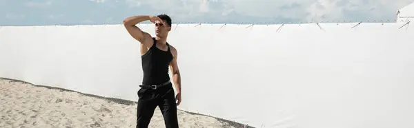 Hombre cubano musculoso en traje negro cubriendo la cara con la mano en Miami, playa sur, pancarta - foto de stock