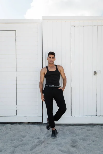 Schöner junger kubanischer Mann in schwarzem Outfit posiert in Miami am Südstrand und blickt in die Kamera — Stockfoto