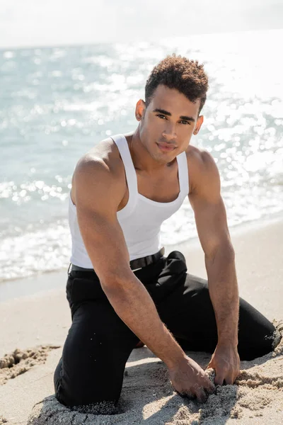 Красивый и атлетичный кубинский мужчина позирует и смотрит в камеру возле океана в Майами Саут Бич — стоковое фото