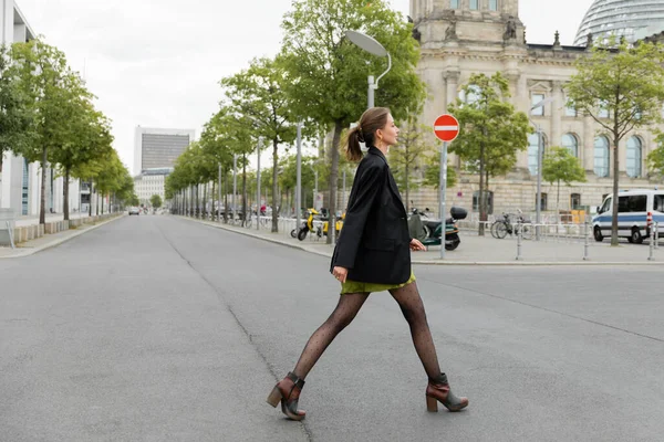 Seitenansicht einer modischen jungen Frau in Kleid und schwarzer Jacke auf der Straße in Berlin, Deutschland — Stockfoto