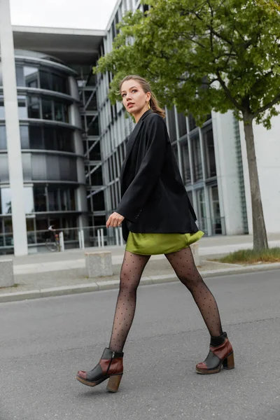 Tutta la lunghezza di donna dai capelli alla moda e fiera in giacca, collant a pois e stivali a Berlino — Foto stock