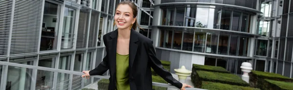 Елегантна і красива жінка в чорній куртці і шовковій сукні посміхається в Берліні, Німеччина, банер — стокове фото