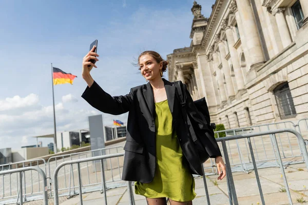 Усміхнена жінка з рюкзаком бере селфі біля будівлі Рейхстагу в Берліні, Німеччина — стокове фото