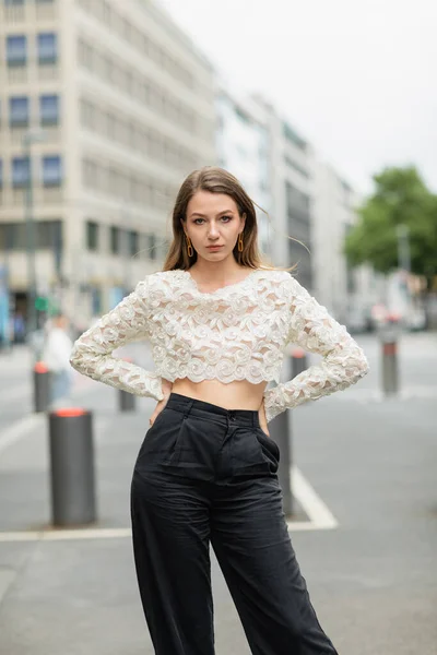 Confident young woman posing in lace top and high waist pants standing on street in Berlin, Germany — Stock Photo