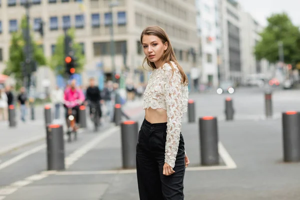 Young woman posing in lace top and high waist pants standing on street in Berlin in daylight — Stock Photo