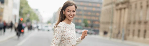 Cheerful young woman in lace top and high waist pants walking on street in Berlin, Germany banner — Stock Photo