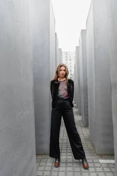 Mujer joven con chaqueta de pie entre el Memorial a los judíos asesinados de Europa en Berlín - foto de stock