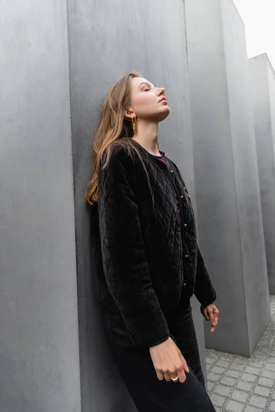 Giovane donna rilassata in giacca in piedi vicino Memoriale agli ebrei assassinati d'Europa durante il giorno a Berlino — Foto stock