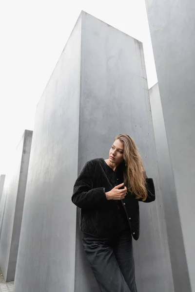 Чесна волохата жінка торкається волосся і дивиться в сторону Меморіалу вбитих євреїв Європи в Берліні — стокове фото