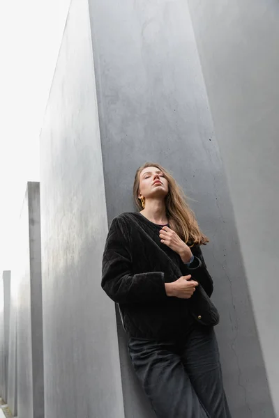 Молода прекрасна волохата жінка в куртці, що стоїть між Меморіалом вбитих євреїв Європи в Берліні — стокове фото