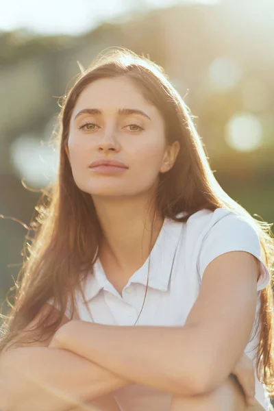 Portrait of pretty young woman with brunette long hair and natural makeup posing in white polo shirt and looking at camera, blurred background, Miami, Florida, iconic city, casual chic, soft filter — Stock Photo