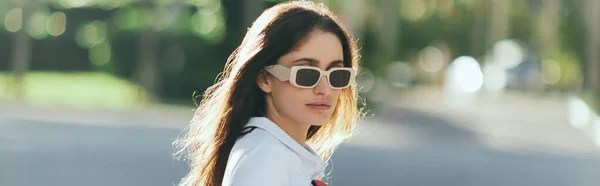 Portrait of stylish young woman with brunette long hair standing in white polo shirt and sunglasses with blurred background, Miami, iconic city, Florida, sunny day, banner — Stock Photo