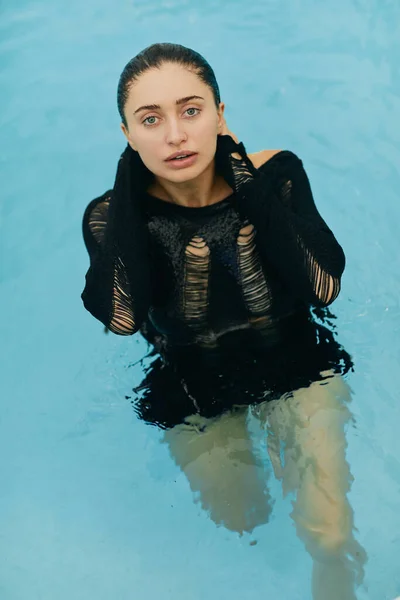 Natural beauty, no makeup look, wet and sexy brunette woman in black knitted outfit posing inside of outdoor swimming pool during vacation in Miami, luxury resort, Florida — Stock Photo