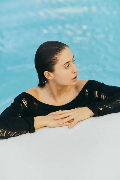 Чудова молода жінка з засмальцьованою шкірою в чорному плавальному костюмі в громадському басейні, виставляючи і отримуючи задоволення від літніх канікул на розкішному курорті в Маямі, без макіяжу. — стокове фото