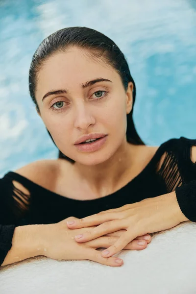 Luxury resort in Miami, beautiful woman with tanned skin looking at camera, inside of public swimming pool, posing and enjoying her summer vacation, no makeup look, portrait — Stock Photo