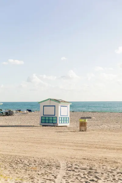 Una cabaña de salvavidas se levanta en una playa de arena cerca del océano, ofreciendo protección y asistencia a los asistentes a la playa.. - foto de stock