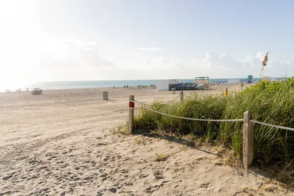 Una tranquilla scena sulla spiaggia con una recinzione, erba lussureggiante e la bellezza di Miami — Foto stock