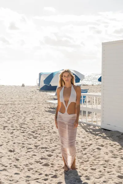 Eine heitere Szene am Miami Beach, als eine junge, schöne blonde Frau anmutig am Sandstrand steht. — Stockfoto
