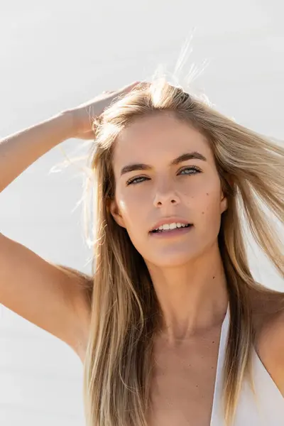 Eine junge, schöne Frau mit langen blonden Haaren trägt ein weißes Oberteil und genießt die Sonne am Strand von Miami. — Stockfoto