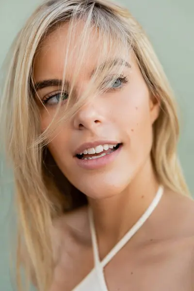 Una joven y hermosa rubia en Miami sonríe, vistiendo una blusa blanca en un día soleado. - foto de stock