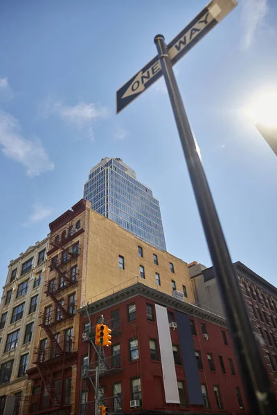 Vue à angle bas du panneau de signalisation indiquant une direction à sens unique, gratte-ciel et bâtiments dans la ville de New York — Photo de stock