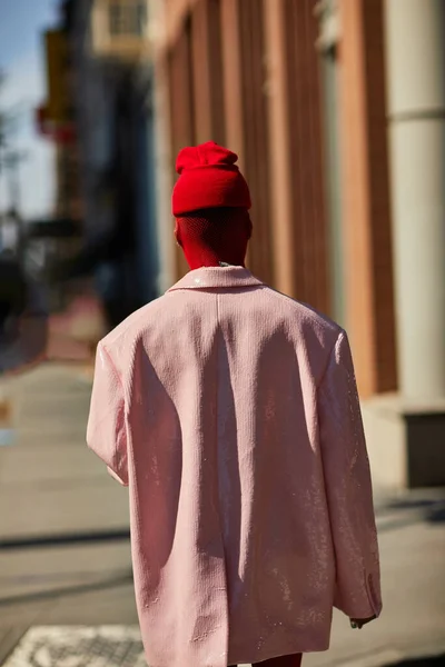 NUEVA YORK, EE.UU. - 26 DE NOVIEMBRE DE 2022: Vista trasera de una persona elegante en gorro rojo caminando por la calle en la ciudad de Nueva York, residente de la metrópoli - foto de stock