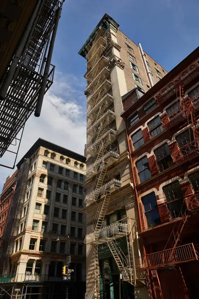 Vista de ángulo bajo del edificio alto con escaleras de escape de incendios en la avenida de la ciudad de Nueva York otoñal - foto de stock