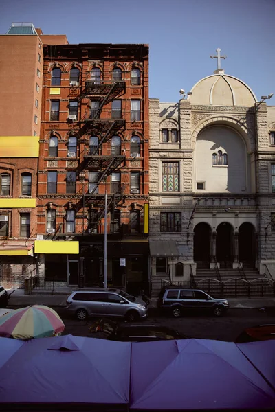 Voitures se déplaçant sur la chaussée près de la brique rouge bâtiment et église dans la ville de New York, atmosphère urbaine — Photo de stock