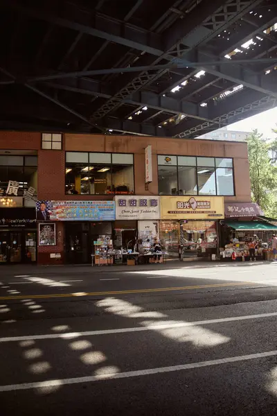 NEW YORK, USA - NOVEMBER 26, 2022: people near shops and street vendors under bridge in chinatown — Stock Photo