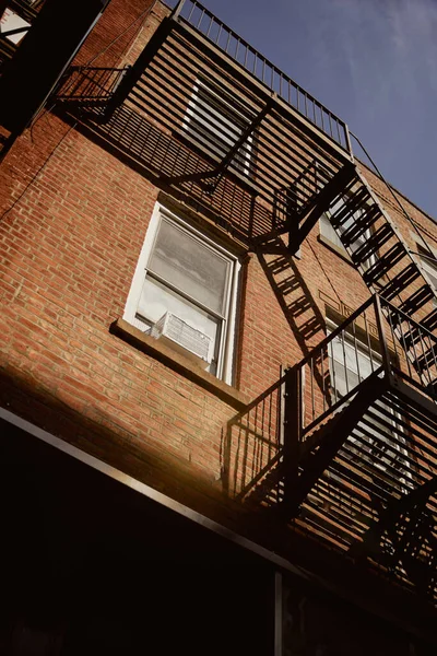 Vue à angle bas du bâtiment en brique avec escalier de secours à New York, architecture urbaine — Photo de stock