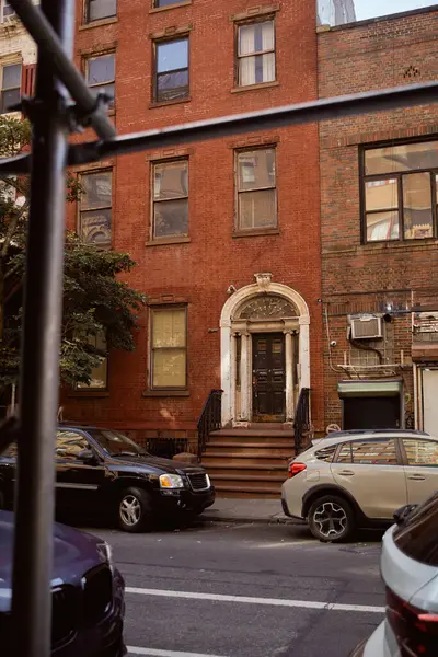Coches cerca de edificio de ladrillo rojo en el icónico distrito de Greenwich Village en la ciudad de Nueva York, escena de la calle - foto de stock