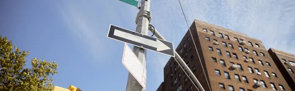 Baixo ângulo de vista do pólo de rua com sinais de trânsito perto de tijolo vermelho edifício em Nova Iorque, banner — Fotografia de Stock
