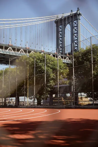 Vista panorámica del puente Manhattan cerca de árboles otoñales y estadio al aire libre en la ciudad de Nueva York - foto de stock