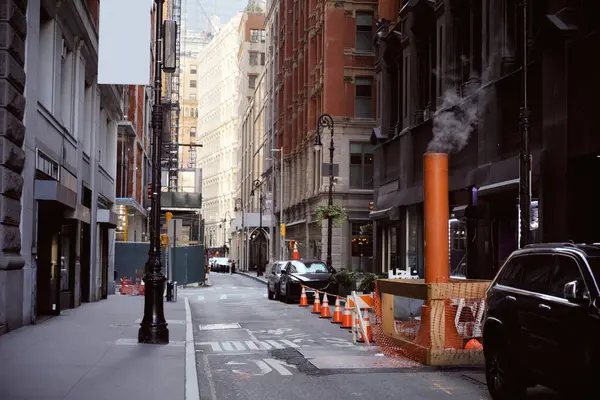 Fumante tubo di ventilazione vicino alle auto parcheggiate sulla stretta strada nella città di New York, atmosfera metropoli — Foto stock