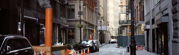 Dampfende Lüftungsrohre in der Nähe von Autos auf einer schmalen Straße in New York City, Großstadtatmosphäre, Banner — Stockfoto