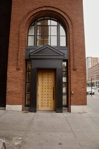 Entrada de edificio de ladrillo con pórtico y ventana de arco en el centro de Nueva York, arquitectura urbana - foto de stock