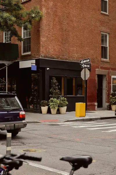 Кирпичное здание с витриной и цветочными горшками рядом с перекрестком в центре Нью-Йорка, уличный пейзаж — стоковое фото