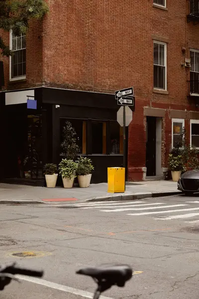 Кирпичное здание с витриной и цветочными горшками рядом с перекрестком в центре Нью-Йорка, городской шарм — стоковое фото
