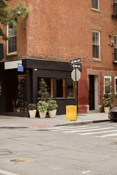 Bâtiment en brique avec devanture et pots de fleurs près du carrefour sur la rue urbaine dans la ville de New York — Photo de stock