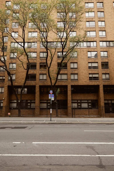 Alberi alti con fogliame caduta vicino edificio in mattoni sulla strada urbana nella città di New York, scena autunnale — Foto stock