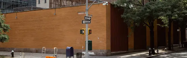 Clôture en brique près des arbres et poteau routier avec panneaux de signalisation sur la chaussée dans la ville de New York, bannière — Photo de stock