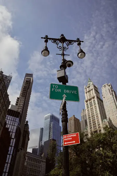 Низький кут зору вуличного полюса з ліхтарями та дорожніми знаками проти хмарочосів у нью-йоркському місті — стокове фото