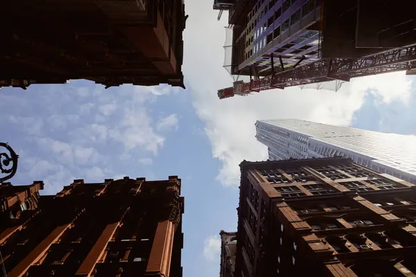 Вид снизу современных и старинных зданий на фоне голубого облачного неба в городе Нью-Йорк, городская сцена — стоковое фото