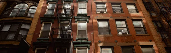 Vista de ángulo bajo de la casa de ladrillo rojo vintage con escaleras de escape de incendios en la ciudad de Nueva York, pancarta - foto de stock
