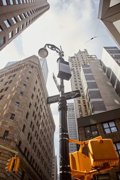 Низкоугольный вид уличного столба с дорожными знаками и светофорами возле высотного здания в новом городе Йорке — стоковое фото
