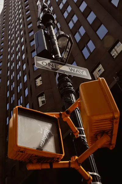 Street pole with road signs and traffic lights near modern building in new york city, low angle view — Stock Photo