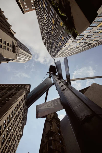 Вид знизу вуличного полюса з дорожніми знаками біля високих будівель на блакитне небо в Нью-Йорку — стокове фото
