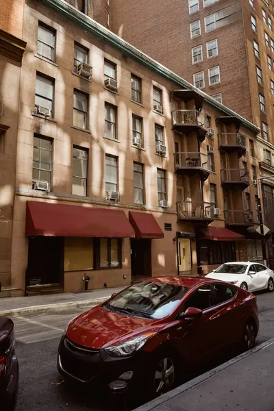 Современные автомобили, припаркованные рядом с каменными зданиями на узкой проезжей части уютной улицы в Нью-Йорке, городской шарм — стоковое фото